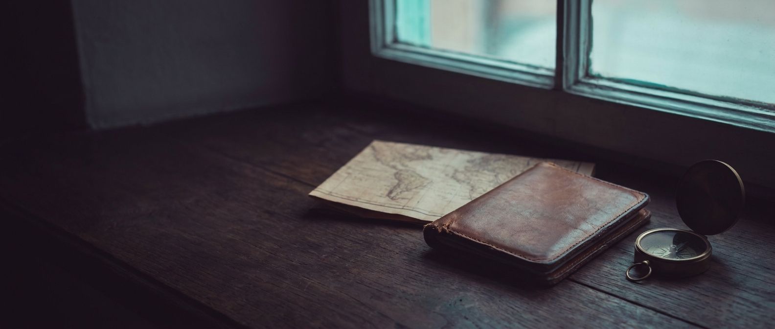 A worn passport, folded map and brass compass in cool pre-dawn light